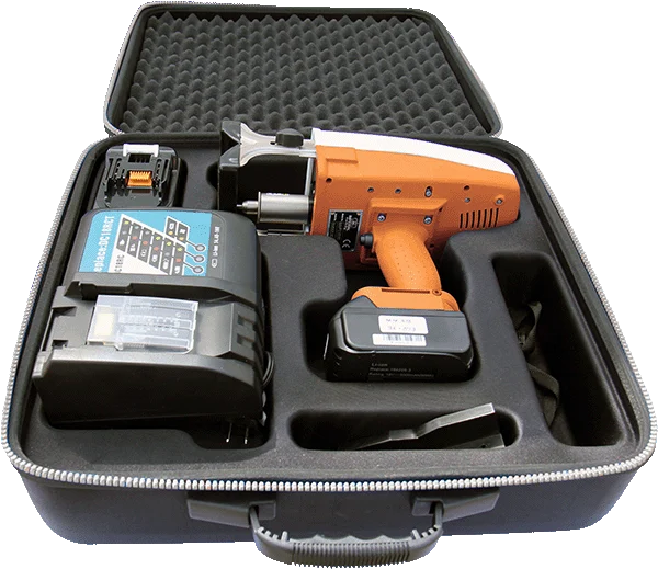 An orange cordless power tool with a battery, charger, and accessories stored in a fitted foam-lined hard case