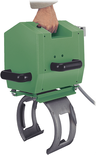 A hand carrying a green, portable industrial device with a curved mounting clamp attached to the bottom
