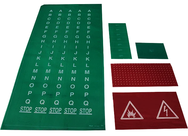 Several green and red mats with various lettered columns, tactile dots, and hazard symbols